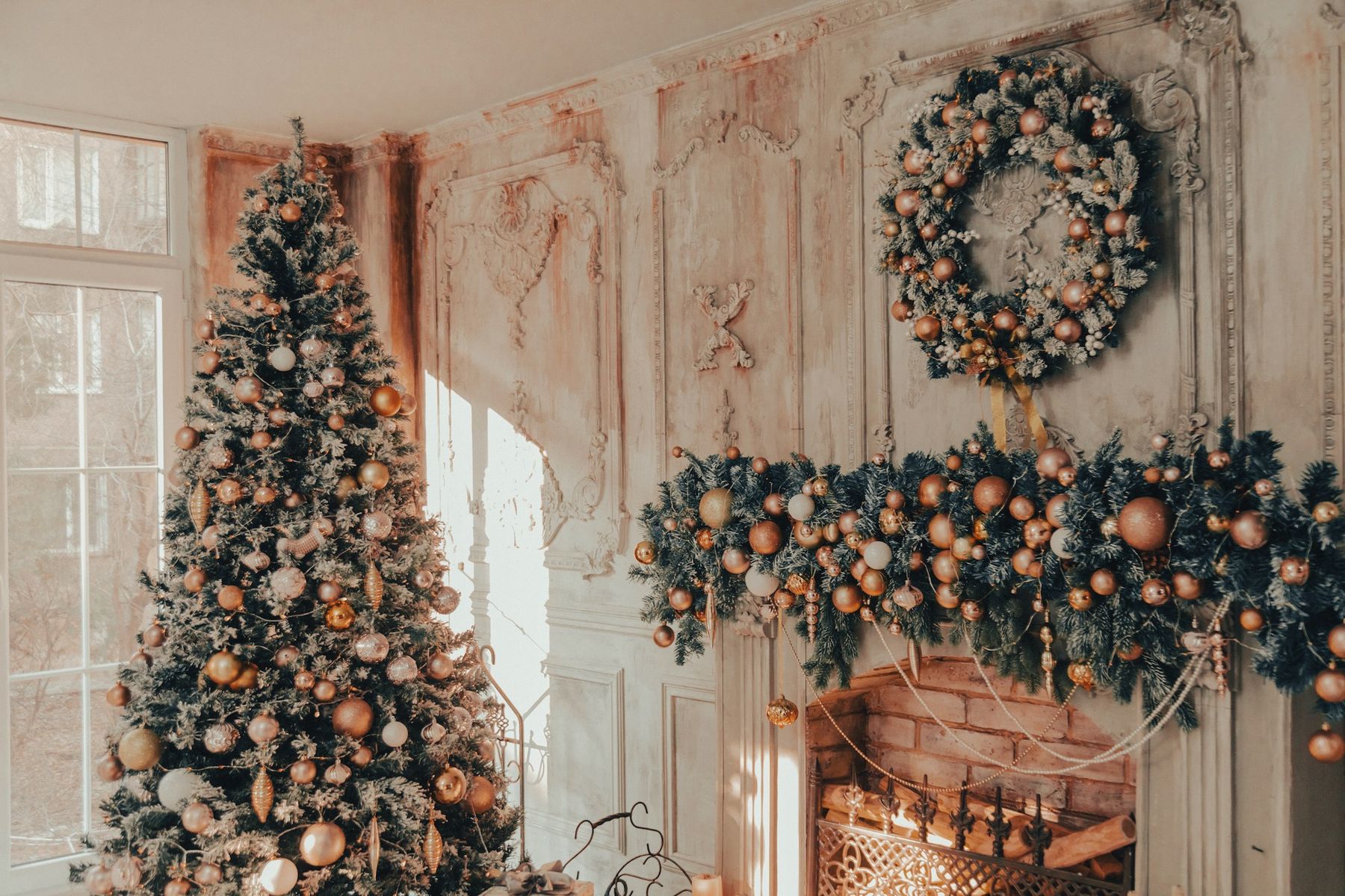 A flocked Christmas tree beside a mantel with a full garland and wreath
